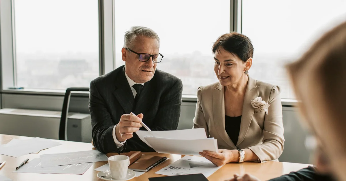 A technician and a client sit at a conference table, reviewing documents and taking notes to document the consultation and plan follow-up actions.