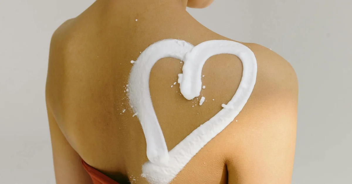 Back view of a person with white numbing cream shaped into a heart on the shoulder.