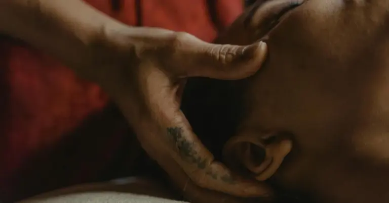 Close-up of a therapist's hands supporting a client's head during a therapy or massage session