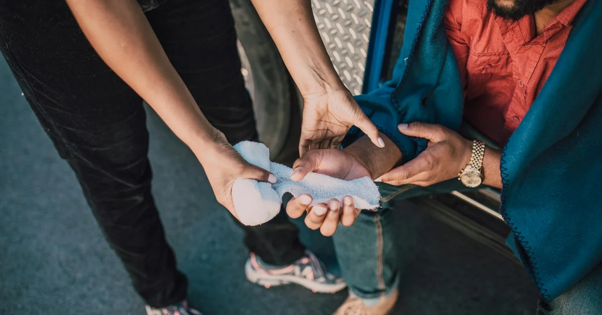 Close-up of hands wrapping a bandage around a finger, illustrating post-laser aftercare