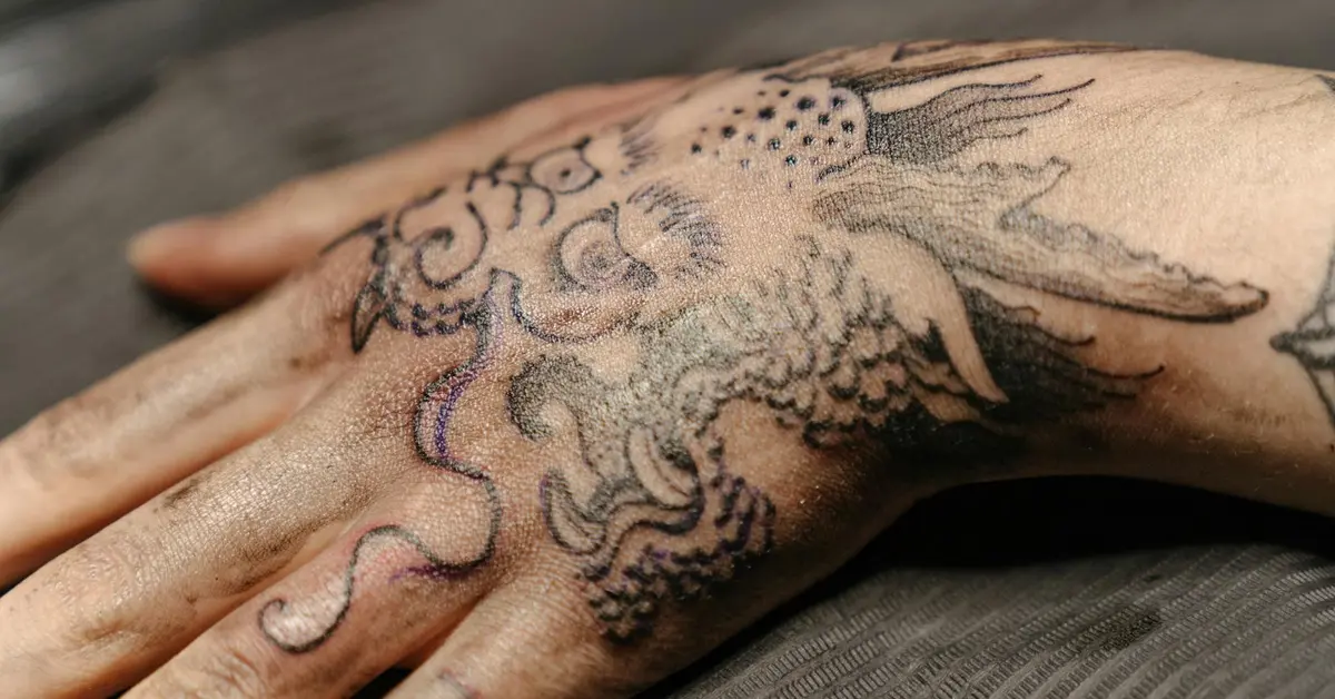 Close-up of a hand with a large black ink octopus tattoo, showing detailed linework and shading on the skin.