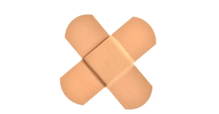 Two beige adhesive bandages arranged in an X shape on a white background