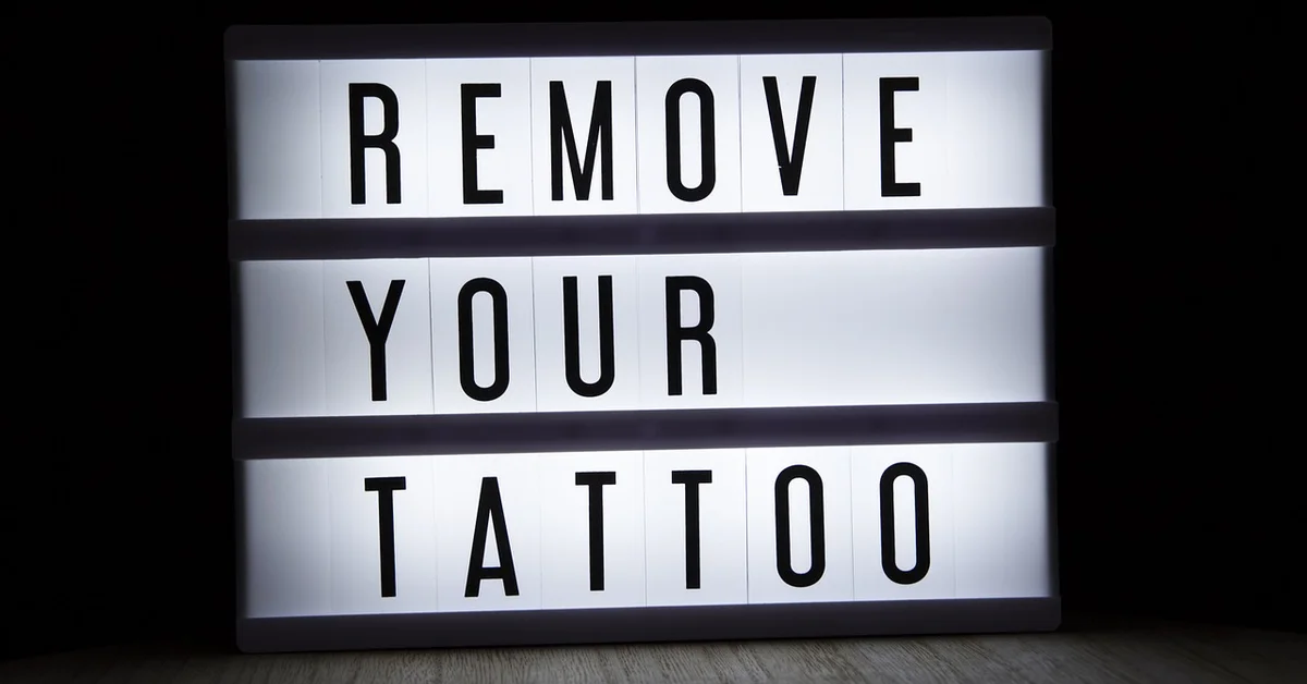 Lightbox sign that reads 'REMOVE YOUR TATTOO' against a dark background, conveying tattoo removal concept using lasers.