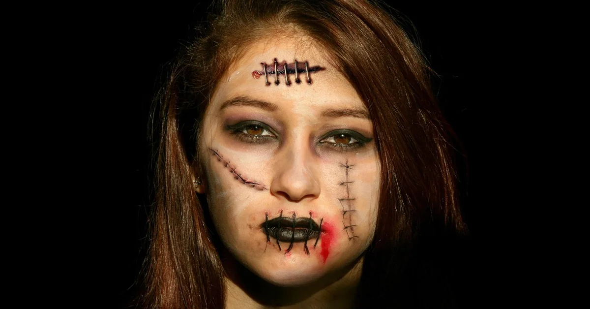 Portrait of a person with makeup simulating stitched scars across the forehead, cheek, and lips.