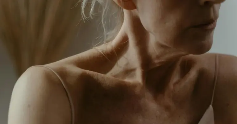 Close-up of a person's neck and shoulder showing natural skin texture and tones.
