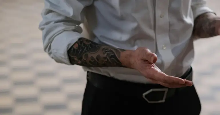 Close-up of a tattooed forearm and hands, suggesting discussion of non-laser tattoo removal methods.