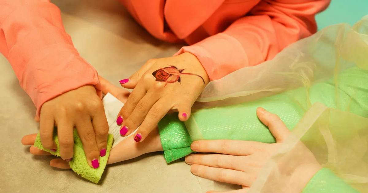Close-up of a wrist tattoo being treated in a non-laser removal session, with hands and protective sleeves visible.