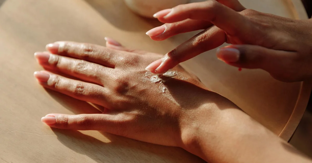 Close-up of hands applying cream to healing skin on the wrist after tattoo removal