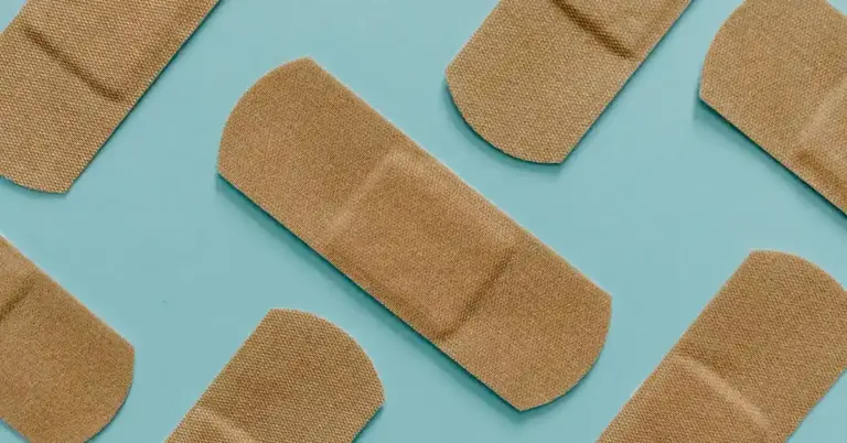 Several beige adhesive bandages scattered on a turquoise background.