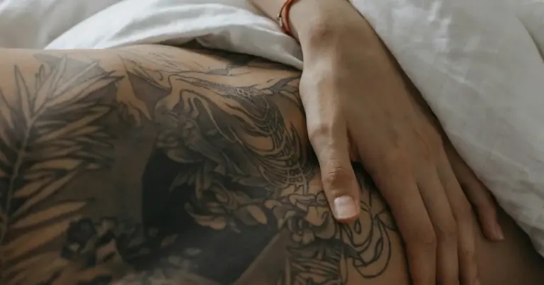 Close-up of tattooed skin with a hand resting on light-colored fabric