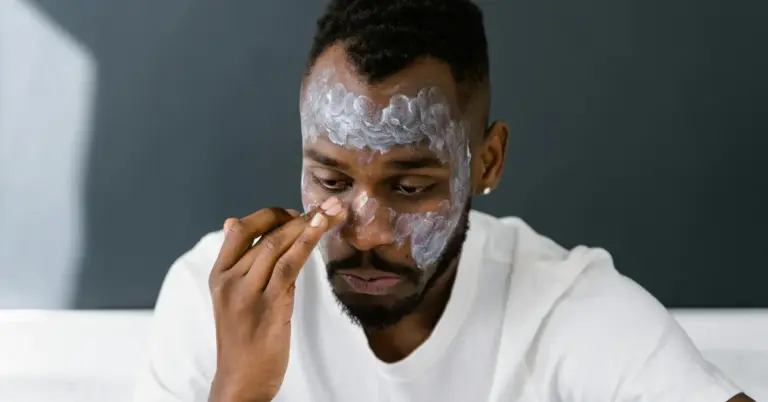 Man applying topical numbing cream to his face in preparation for tattoo removal