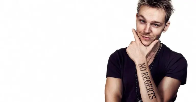 Person with forearm tattoo posing against a white background, suggesting pain management during tattoo removal
