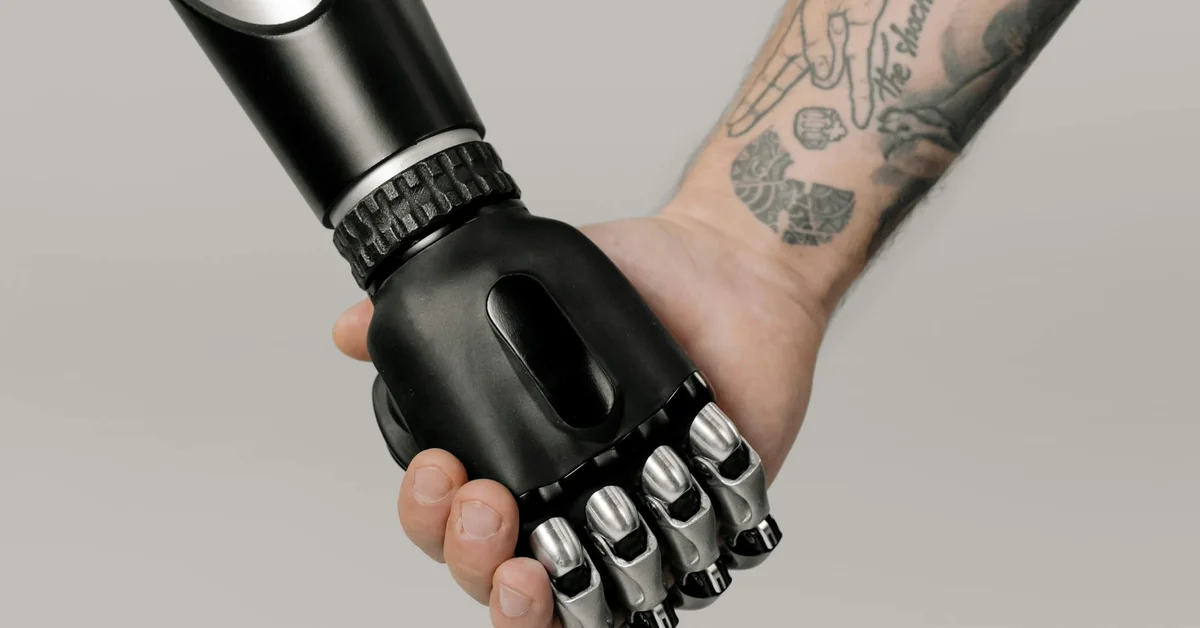 Robotic prosthetic hand gripping a tattooed forearm