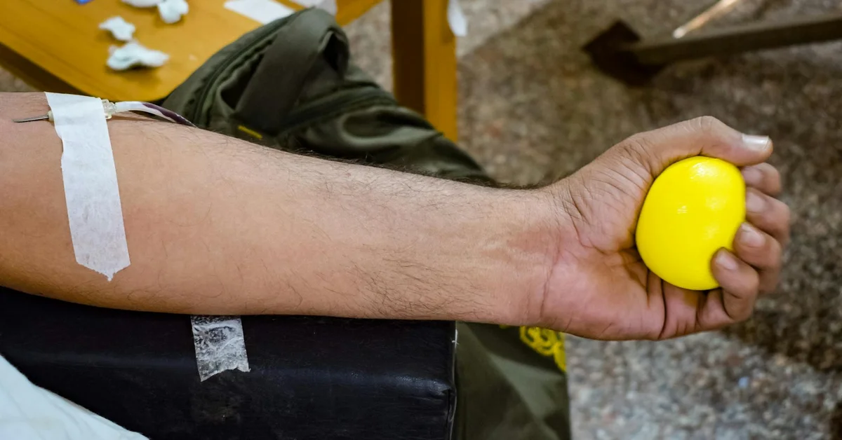 Close-up of a forearm with a white wrap and tape, holding a yellow massage ball, illustrating post-tattoo wrap handling.
