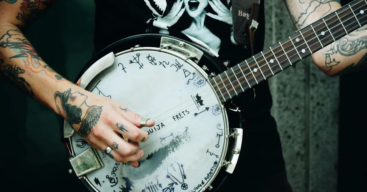 Close-up of tattooed hands playing a banjo