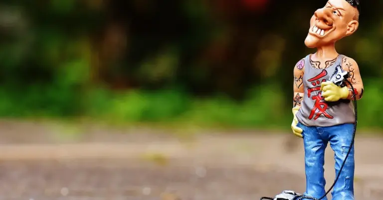 A cartoon-style figurine with multiple tattoos on its torso and arms, standing outdoors with a blurred green background.