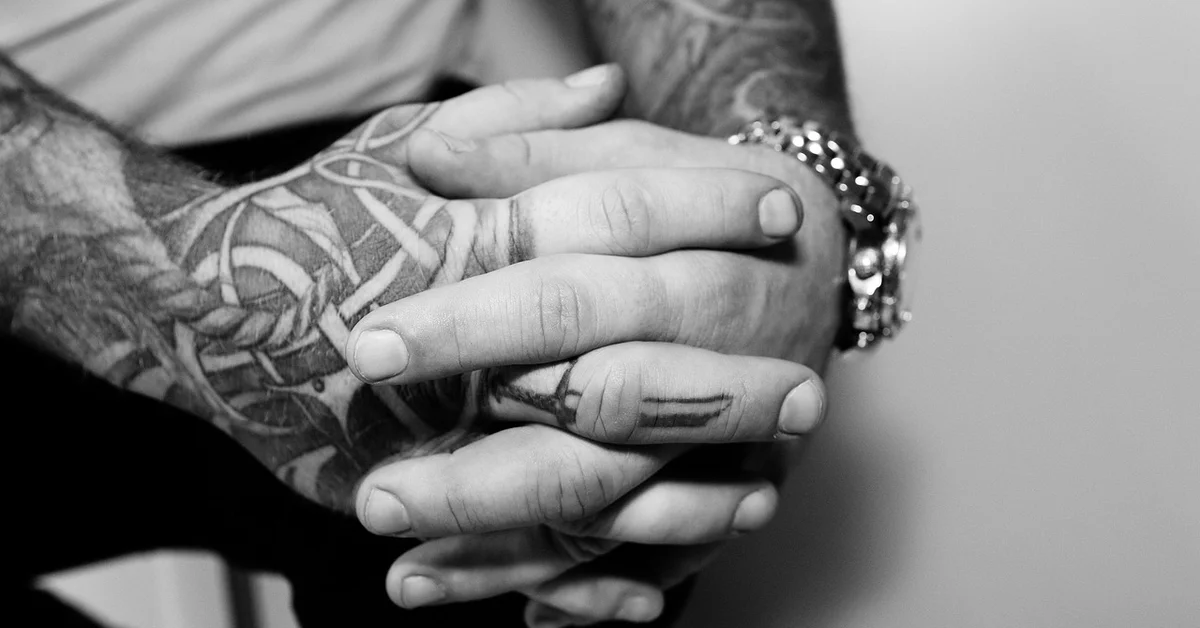 Close-up of tattooed hands clasped together