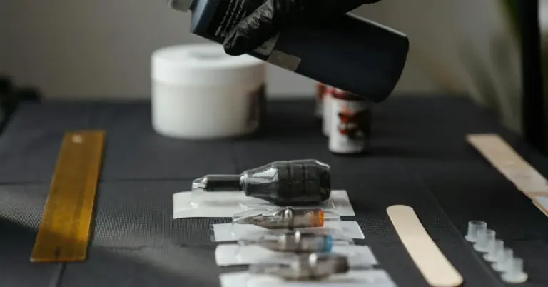 Close-up of tattoo removal equipment on a worktable, including a handheld device, tubes, and supplies with a gloved hand in the background.