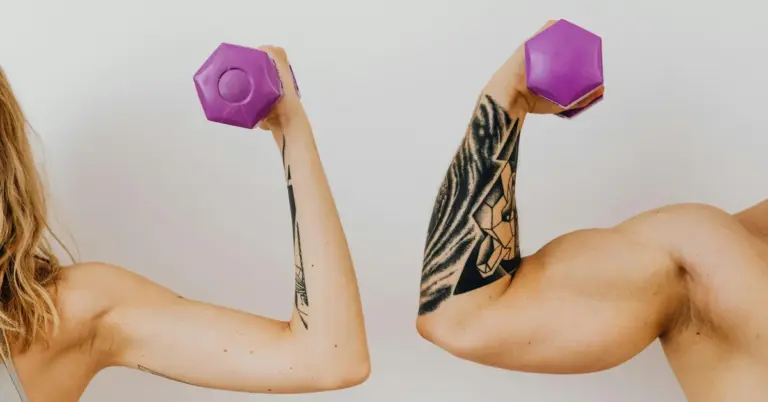 Two people lifting purple hexagonal dumbbells, showing tattooed forearms during a workout.